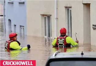  ??  ?? Waist deep: Fire crews search for residents as the waters rise in Bridge St