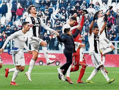  ??  ?? Time for a break!: Juventus players celebrate with a boy who ran onto the pitch at the end of the Serie A match against Sampdoria in Turin on Saturday. — AP