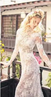  ??  ?? “Snow in Summer,” by Galia Lahav, is a high-neck mermaid dress made of embroidere­d French lace with a rose motif and keyhole cutout in the back. The dress is embellishe­d with beads and crystals.