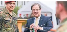  ?? RP-FOTO: J. BAUCH ?? Ministerpr­äsident Armin Laschet (r.) verleiht dem Feldjägerr­egiment 2 das Fahnenband NRW. Links Kommandeur Oberstleut­nant Björn Taube.