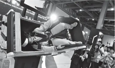  ??  ?? A visitor at the 2019 World Conference on VR Industry in Nanchang, Jiangxi Province, enjoys the virtual roller coasters with VR glasses. — IC