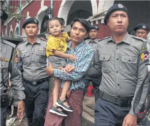  ?? AFP ?? Detained Myanmar journalist Kyaw Soe Oo, 28, carries his daughter as he is escorted by police to the Yangon courthouse on the first day of trial yesterday.