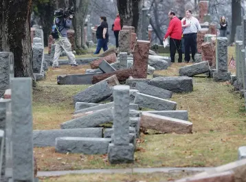  ?? (Tom Gannam/Reuters) ?? RESIDENTS INSPECT more than 170 toppled Jewish headstones after a weekend vandalism attack on Chesed Shel Emeth Cemetery in University City, Missouri, in February.