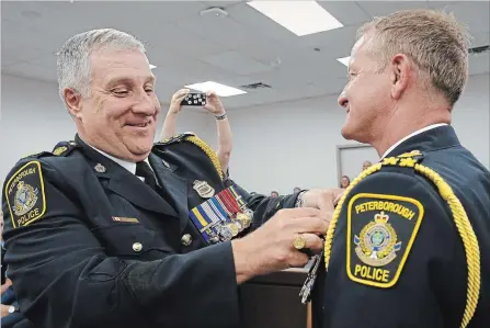  ?? CLIFFORD SKARSTEDT EXAMINER ?? Outgoing city police Chief Murray Rodd assists Scott Gilbert in being sworn in as the ninth police chief of Peterborou­gh.