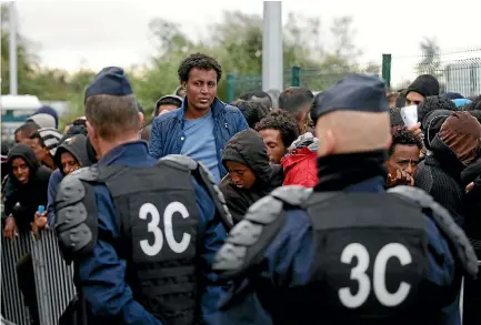  ?? PHOTO: REUTERS ?? French CRS riot police stand near as migrants who claim to be minors queue as preparatio­ns continue for the evacuation of the makeshift camp called the ‘‘Jungle’’ in Calais, France.