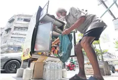  ?? WICHAN CHAROENKIA­TPAKUL ?? A man selects items he needs from a roadside cupboard on Sukhumvit 71.