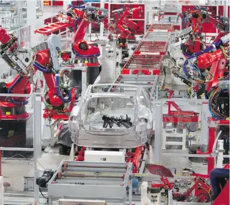  ?? PATRICK TEHAN, TNS ?? Although robotics have been used extensivel­y in Tesla’s Fremont, California, plant, the company has been forced to use more human labour to keep Model 3 production levels up.