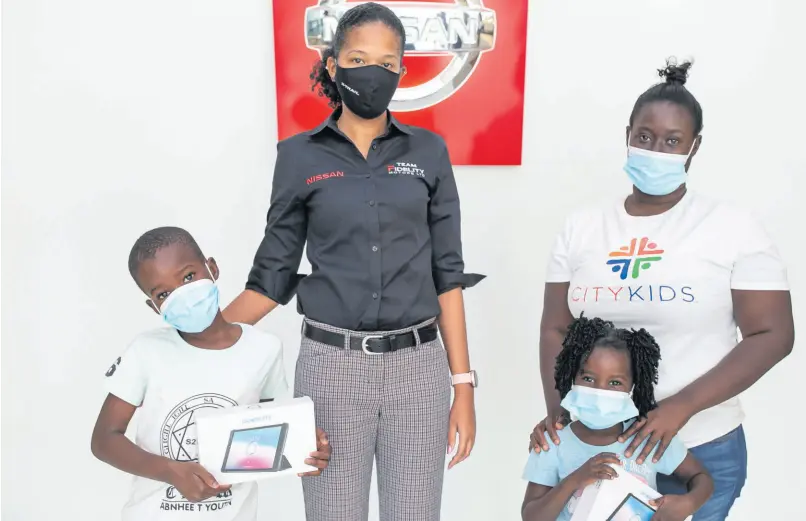  ?? CONTRIBUTE­D ?? City Kids Jamir Bailey (left) and Kimoya Graham receive tablet computers from Melissa Bennett (centre), sales and marketing manager at Fidelity Motors. Parent and teacher Kimone Mckenzie looks on. Fidelity Motors handed over 50 tablet computers to the City Kids Homeschool Programme based in downtown, Kingston. The tablets were courtesy of Smart Mobile Solutions Jamaica and the result of a holiday promotion which saw Fidelity donating a tablet on behalf of every customer who purchased a vehicle in December and January.