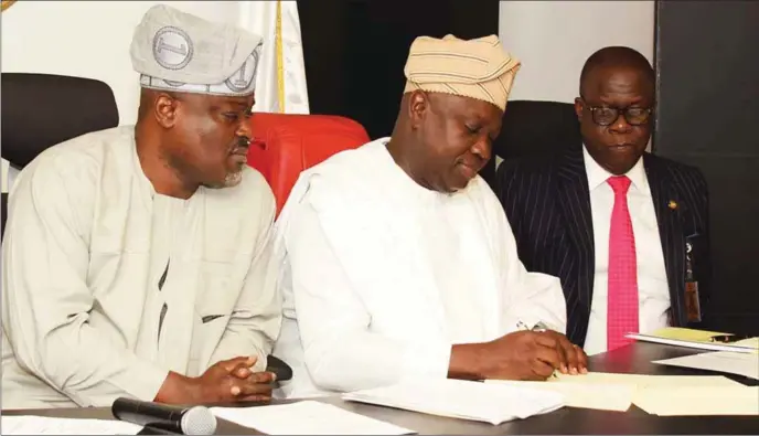  ??  ?? Ambode (middle) signing Lagos State Property Protection Law, 2016, at the State House, Alausa. With him are Speaker of Lagos State House of Assembly, Hon. Mudashiru Obasa (left) and Commission­er for Justice and Attorney-General, Mr. Adeniji Kazeem