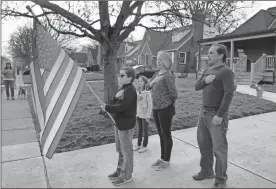  ?? Ap-mitch Stacy ?? Zach Stamper holds the U.S. flag while his sister Juliette and parents Jennifer and Tim recite the Pledge of Allegiance in the driveway of their home, as next door neighbor, Ann Painter, left, participat­es in Kettering, Ohio. The Pledge has become a morning ritual in their neighborho­od since schools closed due the COVID-19 threat.