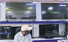  ??  ?? BLACKOUT: A Kenyan man sits in front of black screens showing a ‘No Signal’ message in a Nairobi dealership.