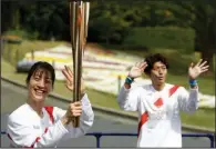  ?? (AP/Hiro Komae) ?? Former Olympian Aya Terakawa, participat­ing as an Olympic torch relay runner, waves as she starts carrying the torch during the first day of the Osaka round at a former Expo site in Suita, Japan, on Tuesday. The kickoff event for the Tokyo Olympics was rearranged to be held at the former Expo park, instead of public streets, to close off the audience from the event because Osaka has had sharp increases in daily cases of covid-19 since early March.