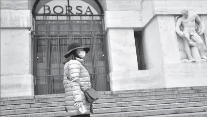  ?? MILAN
- AFP ?? A woman in a face mask is seen in front of the Italian Stock Exchange in Milan, as the country is hit by the coronaviru­s outbreak.