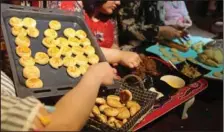  ?? (AP/Nabil al-Jurani) ?? A family prepares cookies for the Eid al-Fitr holiday Monday in Basra, Iraq.