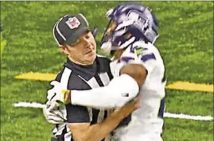  ??  ?? An ecstatic Earl Thomas brings closest referee in for a hug after returning a fumble 34 yards for a Seahawks touchdown, but the official rewards him with a penalty.