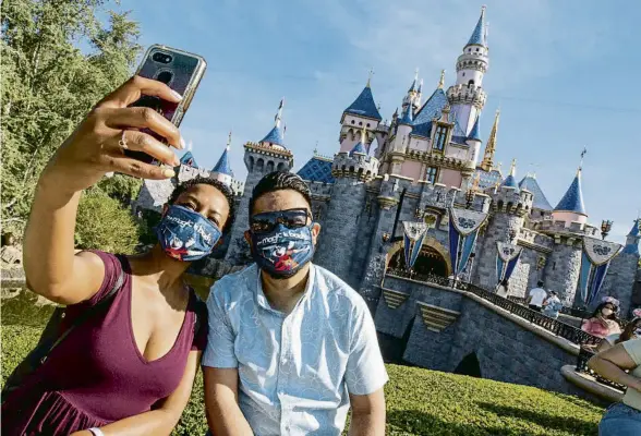  ?? GETTY ?? Una parella amb mascaretes de Mickey Mouse posant davant el castell de la bella dorment a Disneyland, a Anaheim (Califòrnia)