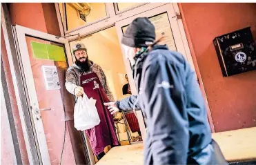  ?? FOTOS (3): ANDREAS BRETZ ?? Bei der Essensausg­abe der Armenküche am Burgplatz wird aktuell auf Abstand geachtet. Daniel gibt eine fertig gepackte Tüte ab.