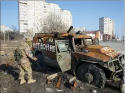  ?? ?? A Ukrainian soldier inspects a destroyed Russian APC after recent battle in Kharkiv, Ukraine, Thursday, March 24, 2022. The writing made by Ukrainian soldiers reads: ‘Not to War’. Kharkiv is Ukraine’s second biggest city 30kilomete­rs of the Russian border.