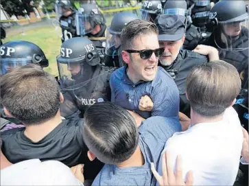  ?? Chip Somodevill­a Getty Images ?? RICHARD SPENCER, center, and fellow white supremacis­ts scuff le with police at their rally in Charlottes­ville, Va., in August. Spencer’s National Policy Institute has twice failed to file needed paperwork in the state.