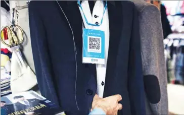  ?? YUYANG LIU/THE NEW YORK TIMES ?? A QR code hangs on a suit in a tailor shop that supports Alipay, in Shanghai, on July 12. China is systematic­ally doing away with paper money and coins.