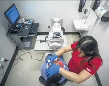  ?? Photograph­s by David McNew For The Times ?? BEA TOMAYO, standing, applies drops to dilate Juana Lorez’s eyes before a diabetic retinopath­y screening. A program led by Dr. Lauren Daskivich helps ease the backlog of the tests for diabetics in L.A. County.