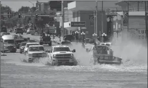  ?? The Associated Press ?? TURN AROUND DON’T DROWN: Traffic drives through flood water across U.S. 81 in downtown Kingfisher, Okla., on Tuesday prior to law enforcemen­t diverting traffic.