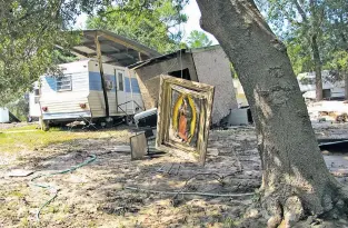  ?? JASON DEAREN/THE ASSOCIATED PRESS ?? A painting of the Virgin de Guadalupe hangs from a tree branch Friday in a Crosby, Texas, neighborho­od wiped out by Harvey’s floodwater­s. Residents returning to the working class mostly Hispanic neighborho­od Friday for the first time found their homes...