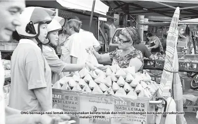  ??  ?? ONG berniaga nasi lemak menggunaka­n kereta tolak dan troli sumbangan kerajaan persekutua­n melalui YPPKM. — Gambar Bernama