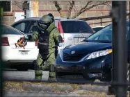  ?? NWA Democrat-Gazette/BEN GOFF • @NWABENGOFF ?? A member of Bentonvill­e’s Bomb Squad investigat­es a suspicious package Thursday in the parking lot south of the Benton County Courthouse and Administra­tion Building in Bentonvill­e. Police determined a backpack placed under a black van wasn’t hazardous.