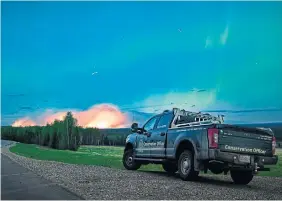  ?? MINISTRY OF WATER, LAND AND RESOURCE STEWARDSHI­P VIA THE CANADIAN PRESS ?? The aurora borealis shines in the sky as a wildfire burns near Fort Nelson, B.C., Saturday. Officials said the Parker Lake blaze, one of three major wildfires in the area, was started by a tree blown down by winds falling onto a power line.