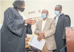  ??  ?? Paul Rusesabagi­na, handcuffed, discusses his case with two lawyers he picked from a list supplied by the government in Kigali.