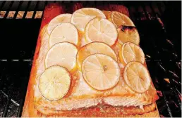  ?? [PHOTO BY ELIZABETH KARMEL/AP] ?? Grilled salmon with lemon slices.