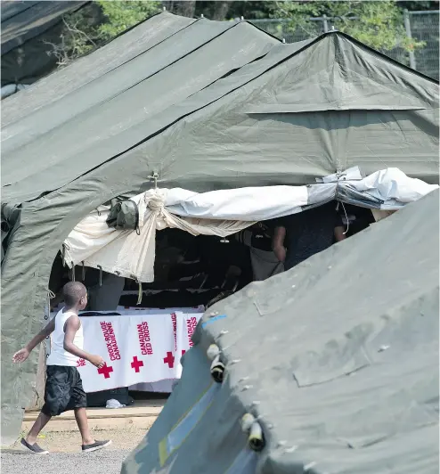  ?? PAUL CHIASSON / THE CANADIAN PRESS FILES ?? A young asylum seeker walks through a temporary camp near Saint-Bernard- de-Lacolle, Que.