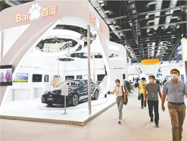  ?? WANG ZHAO / AFP VIA GETTY IMAGES ?? People walk by the Baidu booth at the China National Convention Centre in Beijing. Baidu plans to spend US$7.7 billion on smart-car technology.