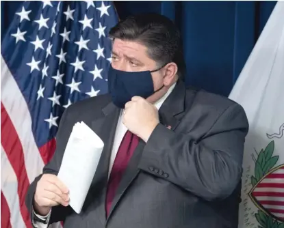  ?? PAT NABONG/ SUN- TIMES ?? Gov. J. B. Pritzker puts on a mask after announcing new statewide mitigation­s to curb the spread of the coronaviru­s.