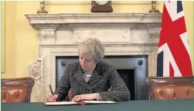  ?? Christophe­r Furlong ?? > Theresa May signs the official letter invoking Article 50