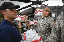  ?? JOE RAEDLE / GETTY IMAGES ?? Puerto Rico National Guard members transfer water from a helicopter to hurricane survivors last week in Lares, Puerto Rico, in the aftermath of Hurricane Maria.