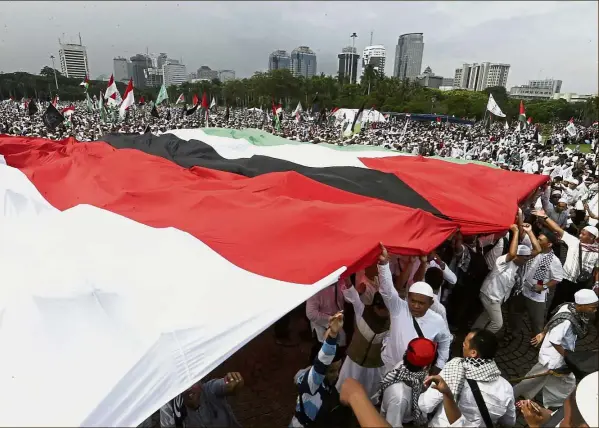  ?? — AP ?? Protesters holding Indonesian and Palestinia­n flags during a rally – against US President Donald Trump’s recognitio­n of Jerusalem as Israel’s capital – at Monas, the national monument, in Jakarta.