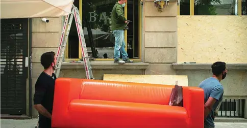  ?? ENRIC FONTCUBERT­A ?? La crisis se ha cebado especialme­nte con el sector turístico. En la imagen, operarios cierran con maderas las ventanas de un hotel que ha decidido a cerrar sus puertas