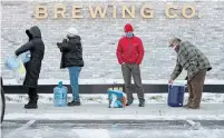  ?? JAY JANNER AUSTIN AMERICAN-STATESMAN VIA THE ASSOCIATED PRESS ?? People wait in line to fill up their containers with water at Meanwhile Brewing Company in Austin, Texas, on Friday.