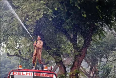  ?? REUTERS ?? A firefighte­r sprays water onto trees to fight air pollution in Delhi, on Tuesday .