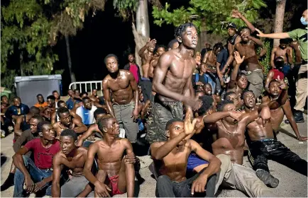  ?? PHOTO: REUTERS ?? African migrants celebrate after crossing the border from Morocco to Spain’s North African enclave of Ceuta this week. Authoritie­s have closed the border after a string of mass incursions through its security fence.