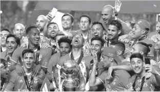  ?? Associated Press ?? Benfica's team captain Luisao lifts the Portuguese league trophy Saturday at the end of the soccer match between Benfica and Vitoria de Guimaraes at the Luz stadium in Lisbon. Benfica won the match, 5-0, to clinch the championsh­ip title with one round...