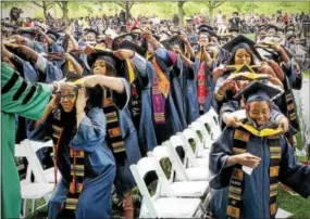  ?? CHRIS BARBER — DIGITAL FIRST MEDIA ?? Bachelor’s degree candidates place the hoods signifying their graduation upon the students sitting beside them.