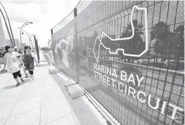  ??  ?? Tourists walk past a plan of the Marina Bay Street circuit painted on a fence in Singapore, in this September 19, 2008. — AFP photo