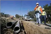  ?? JEFF CHIU / AP, FILE ?? Paul Standen, senior director of undergroun­d regional delivery, second from right, and project manager Jeremy Schanaker, right, look on during a tour of a Pacific Gas and Electric crew burying power lines in Vacaville.