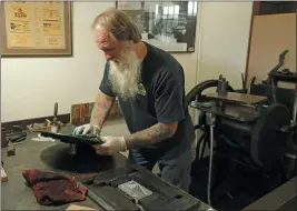  ?? PHOTOS BY TED S. WARREN — THE ASSOCIATED PRESS ?? Loren Ackerman cleans the ink plate of the 1890s-era press he uses to print wooden money on May 21 in Tenino, Wash.