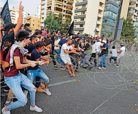  ?? AFP ?? Lebanese demonstrat­ors try to break through barbed wire barriers set by security forces at a rally called by an Islamist group to protest comments by the French President seen as offensive to Islam, near the residence of the French Ambassador in Beirut, on Friday.
