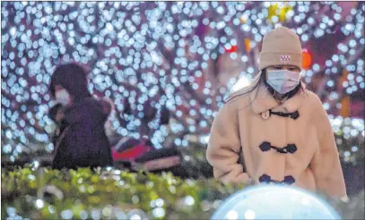  ?? Mark Schiefelbe­in The Associated Press ?? People walk past a light display Tuesday in Beijing, where more than a dozen communitie­s and villages are under lockdown.