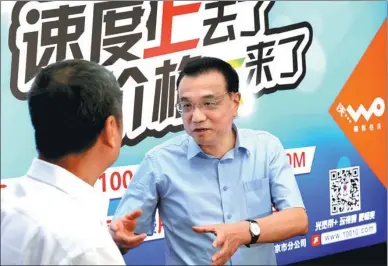  ?? WU ZHIYI / CHINA DAILY ?? Premier Li Keqiang chats with a China Unicom user at the phone company’s headquarte­rs in Beijing on Monday. Li pressed the three largest phone companies earlier this year to make their services more affordable. The board behind Li says of China...